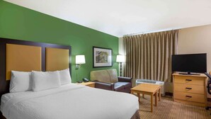 A hotel room with a large bed, a desk, a chair, a television, and a window with curtains. - Extended Stay America Suites - Charleston - Airport (North Charleston)