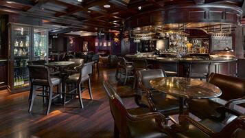 A bar area with wooden furniture, a piano, and a variety of bottles.