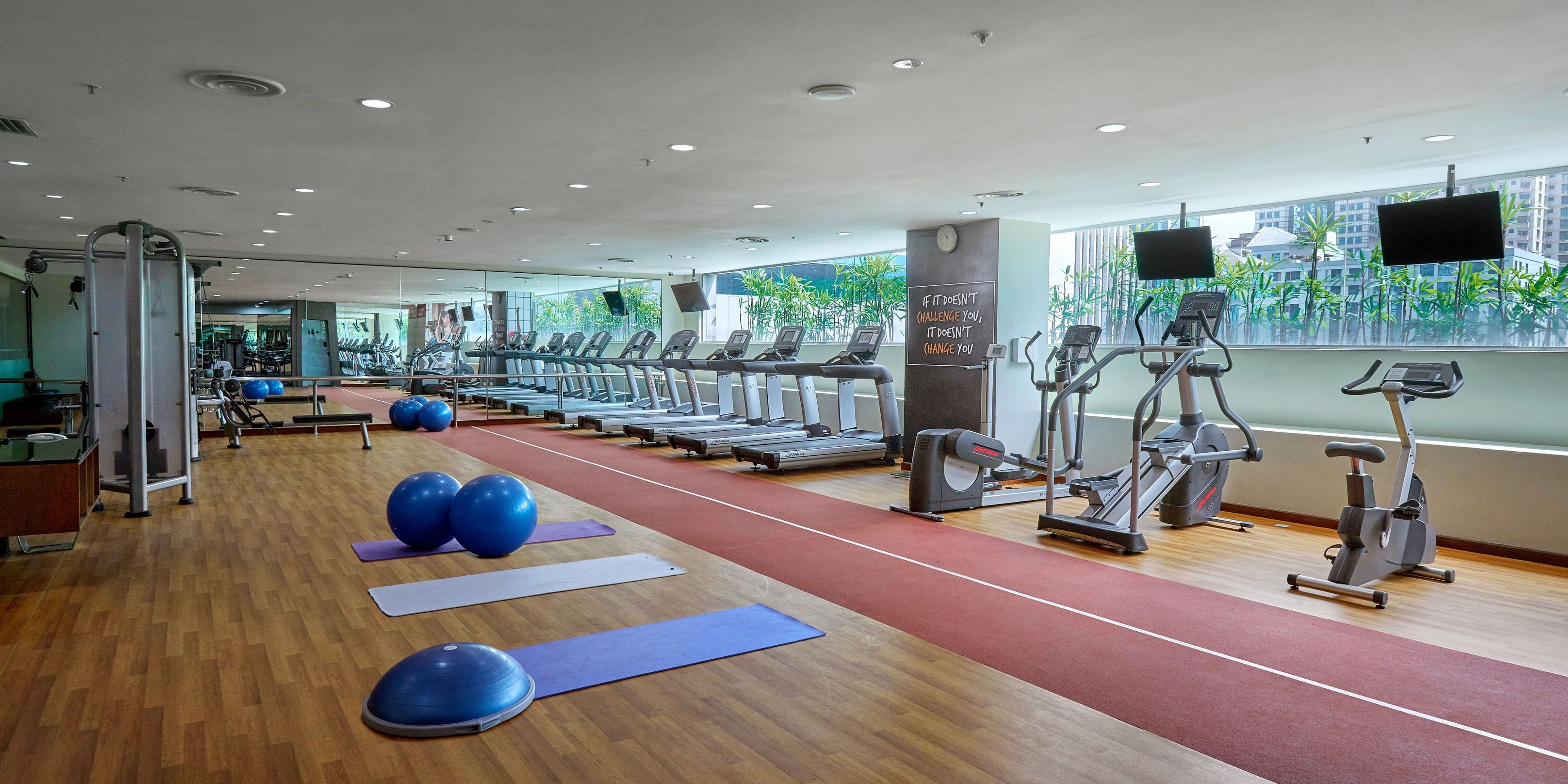 Un gimnasio con cintas de correr, elípticas y pelotas de ejercicio.