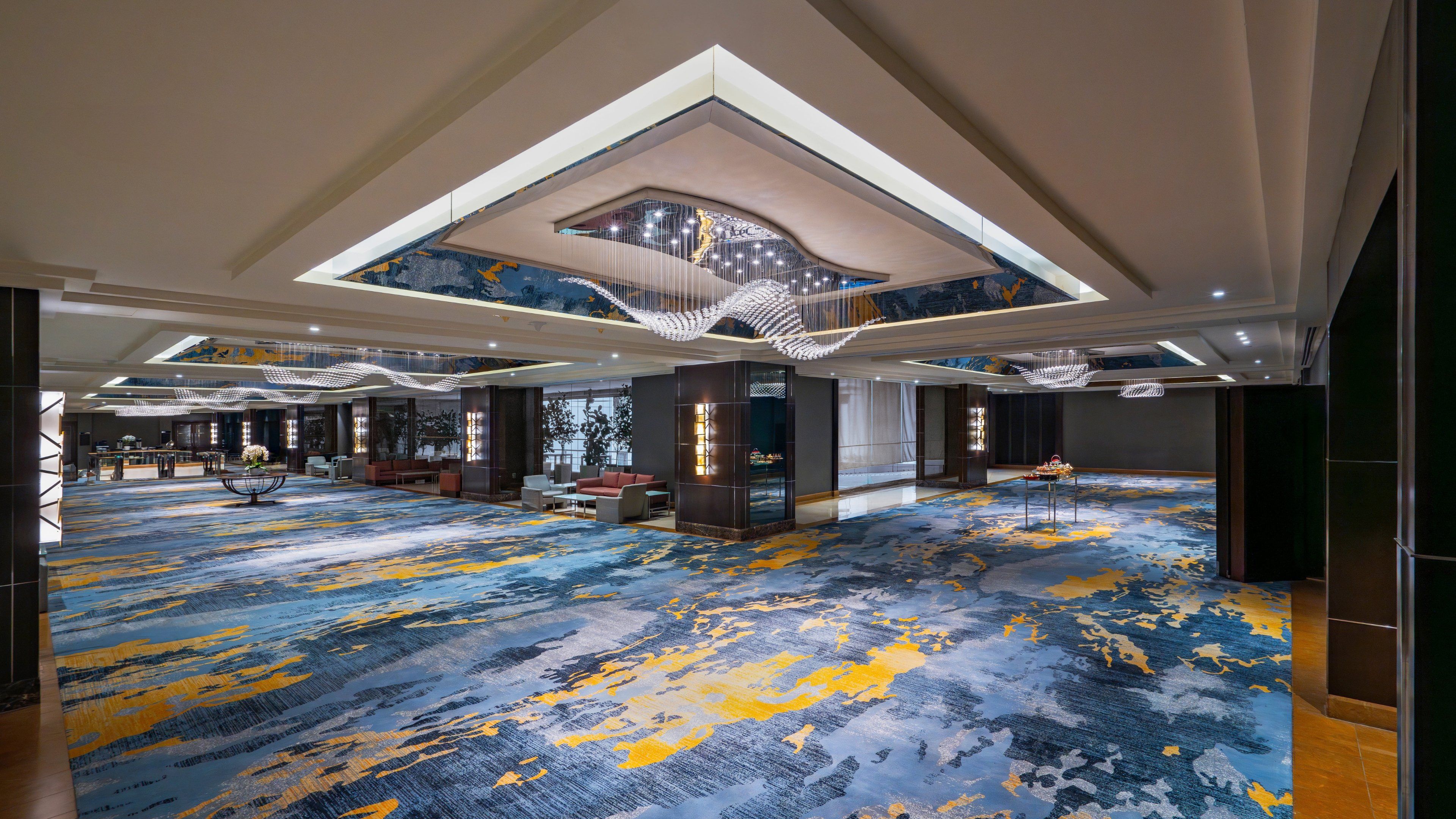 A spacious lobby with a high ceiling, a patterned carpet, and a reception desk.