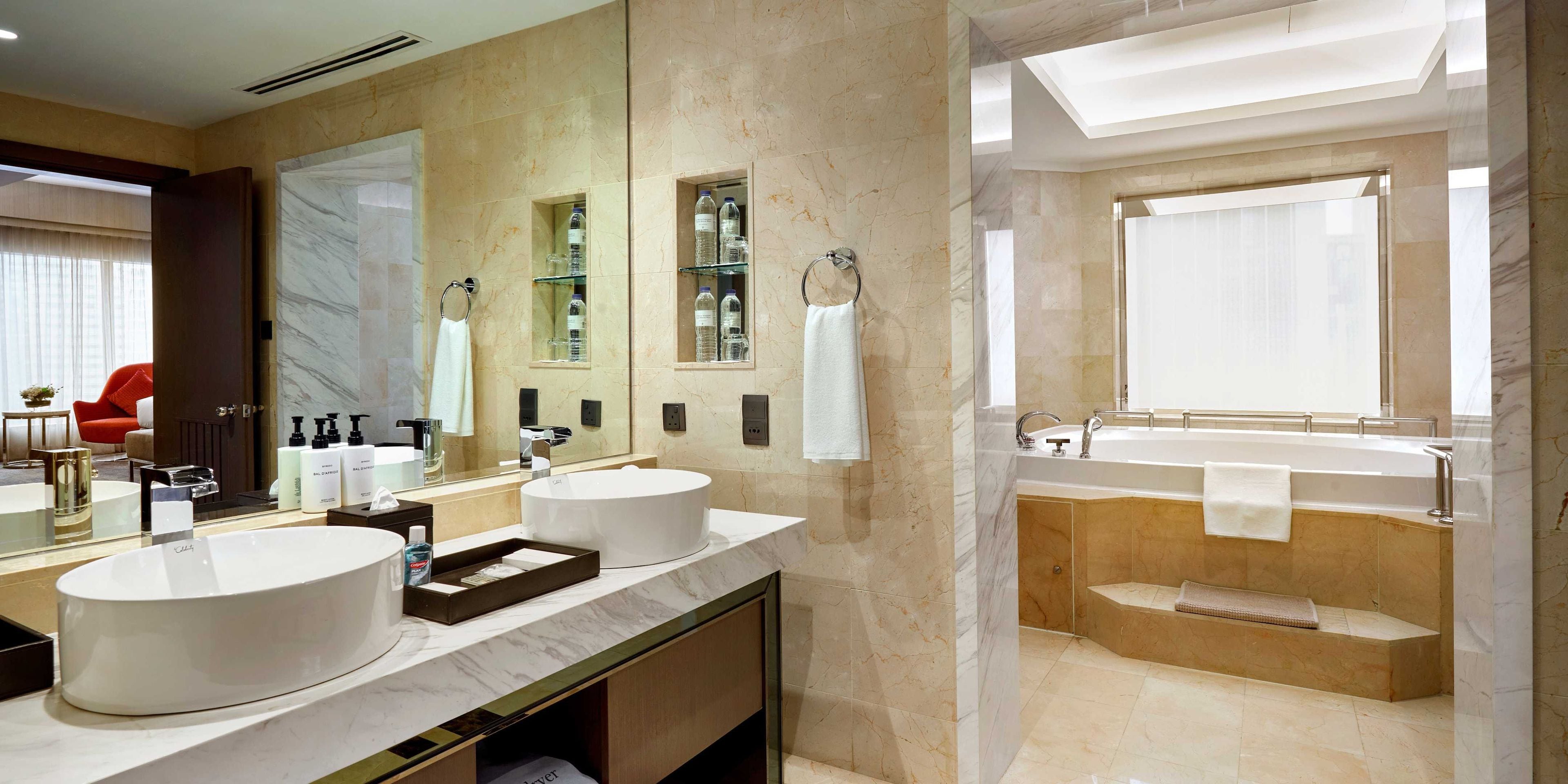 A modern bathroom with two sinks, a large mirror, and a bathtub.
