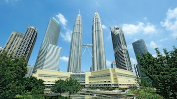 A cluster of high-rise buildings with a prominent central tower, surrounded by greenery and a body of water.