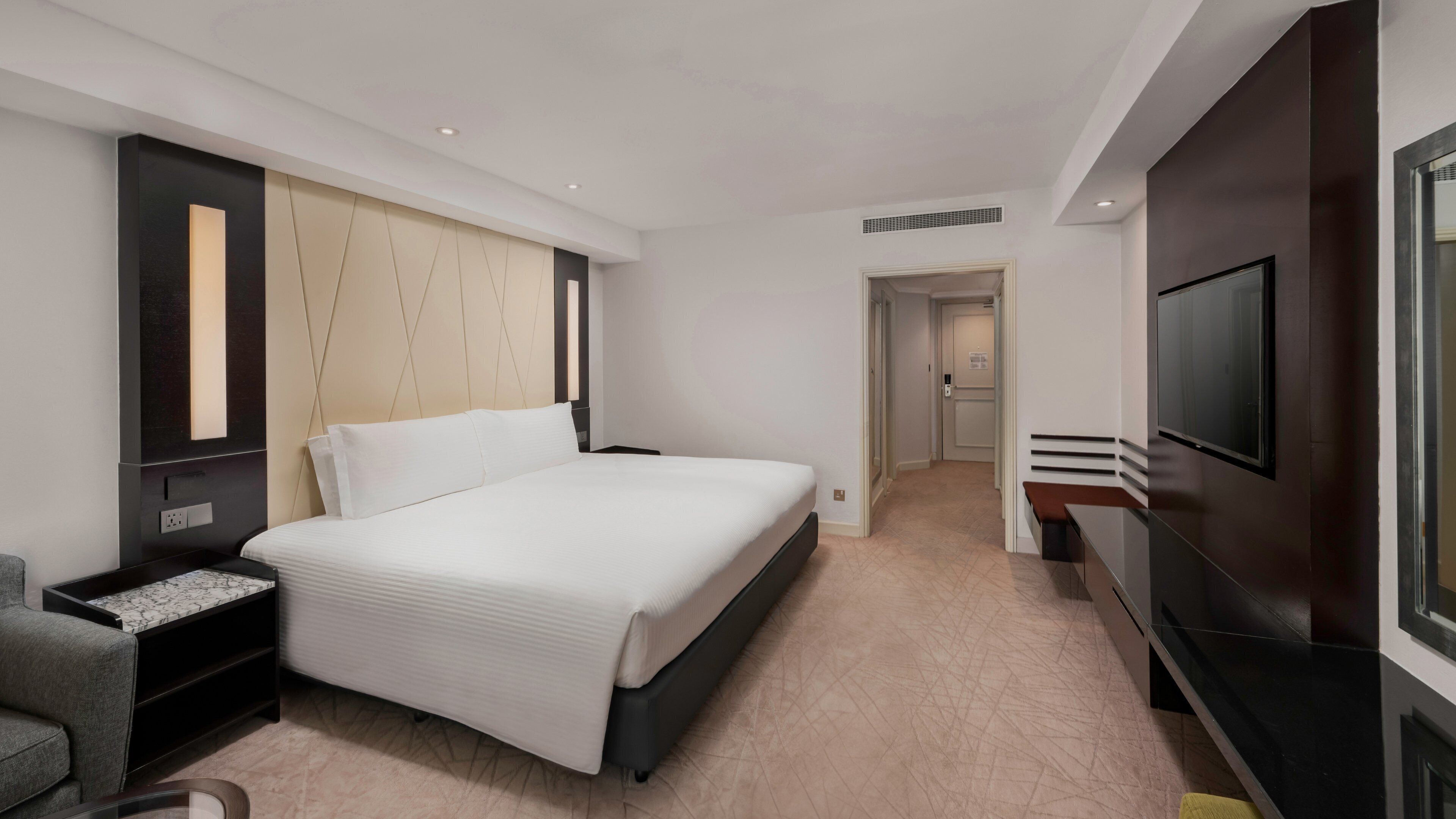 Une chambre d’hôtel moderne équipée d’un grand lit, d’une télévision, d’un bureau et d’une chaise.