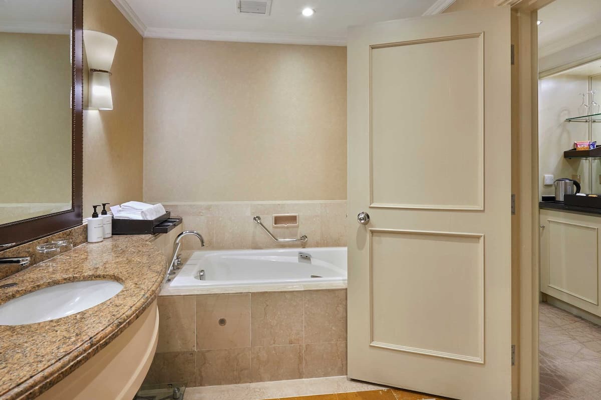 A bathroom with a sink, mirror, and bathtub.
