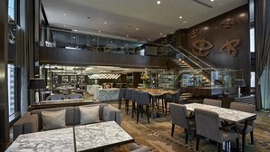 Eine moderne Hotelhalle mit Zwischengeschoss, Sitzbereichen, einer Treppe und einer Bar.