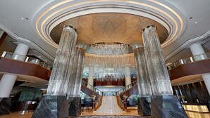 Eine prachtvolle Lobby mit einer zentralen Treppe, großen Säulen und einem Kronleuchter.