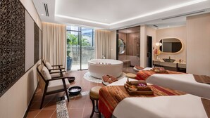 Ein modernes Hotelzimmer mit einer großen Badewanne, zwei Sofas, einem Esstisch und einem Badezimmer mit großem Spiegel und Waschbecken.