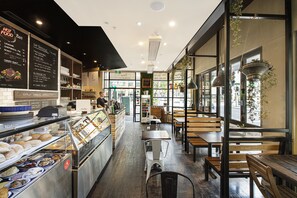 Eine Bäckerei mit einer Auslage voller Gebäck und einer Tafel, die Produkte wie Croissants und Donuts anbietet.
