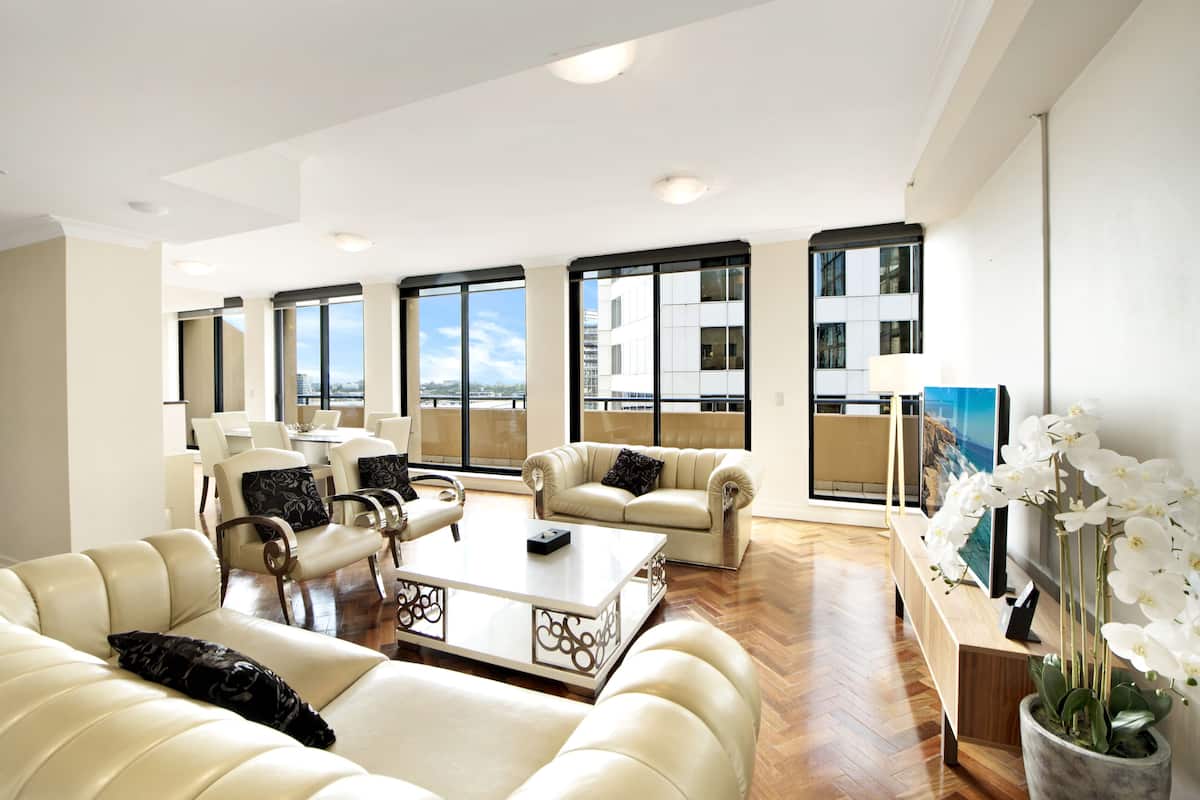 Ein großzügiges Wohnzimmer mit einem großen Fenster, einem Sofa, einem Couchtisch und einem Fernseher.