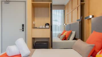 A hotel room with a bed, a desk, a wardrobe, and a window with curtains.
