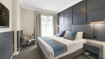 Une chambre d’hôtel moderne avec un grand lit, une table de chevet, une télévision et une vue sur l’extérieur.