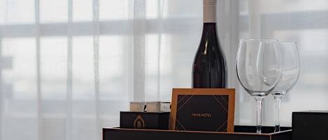 Una botella de vino, dos copas y una caja con la marca, todo sobre una bandeja.