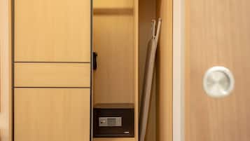 A wooden wardrobe with a black safe, a towel, and a door handle.