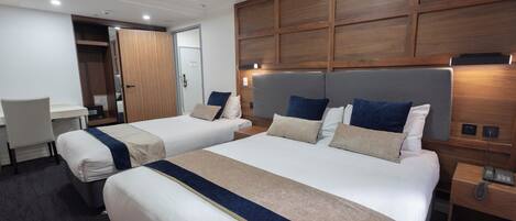 Una habitación de hotel con dos camas, un escritorio y un armario.