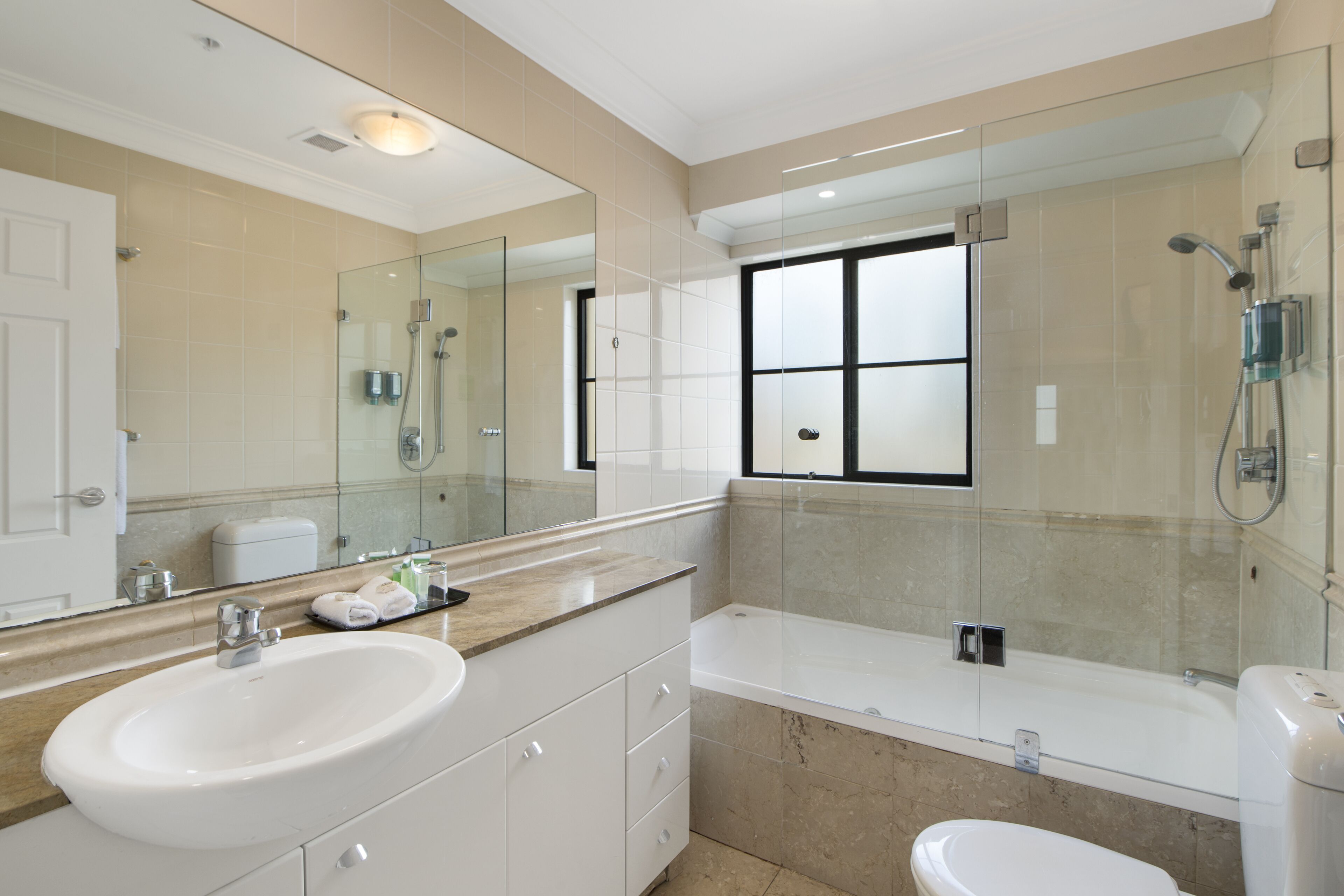 Ein modernes Badezimmer mit großem Spiegel, Waschbecken, Badewanne und Toilette.