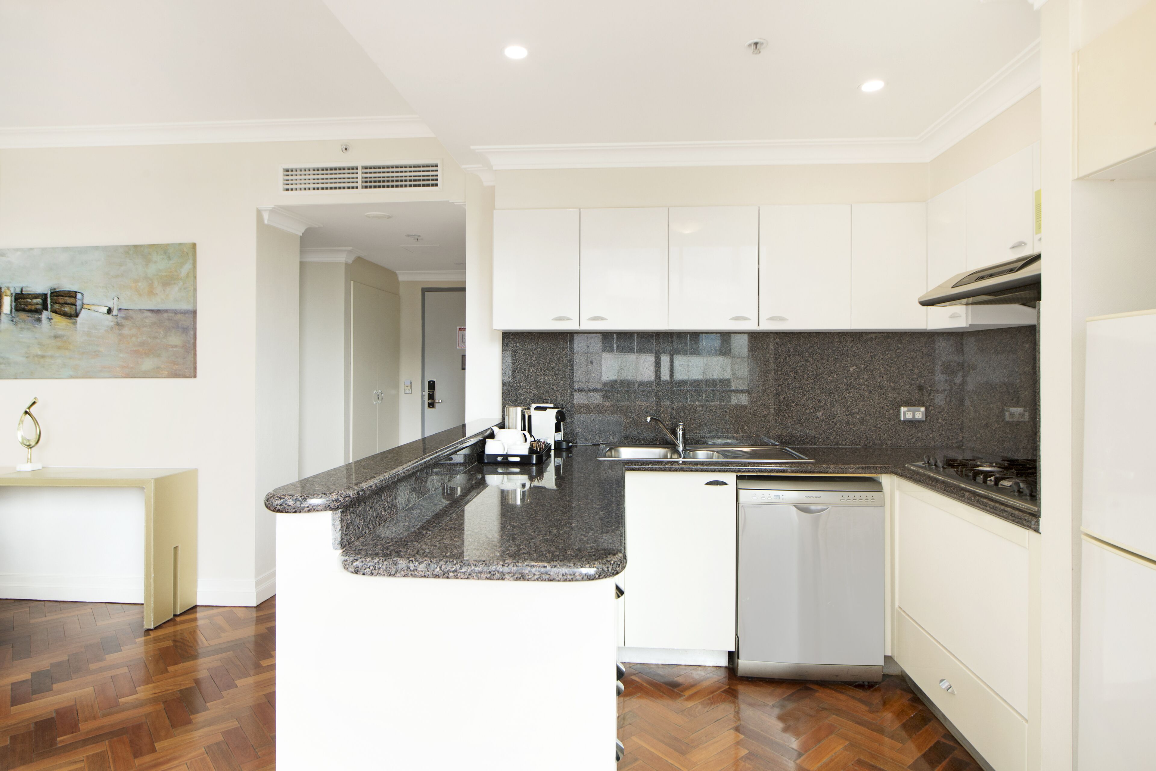 A modern kitchen with white cabinets, a granite countertop, and a dishwasher.
