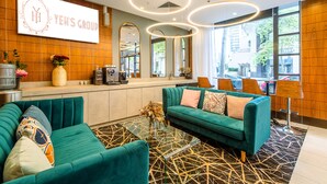 Een moderne hotel lobby met een groene bank, een koffiehoek en een receptiebalie.