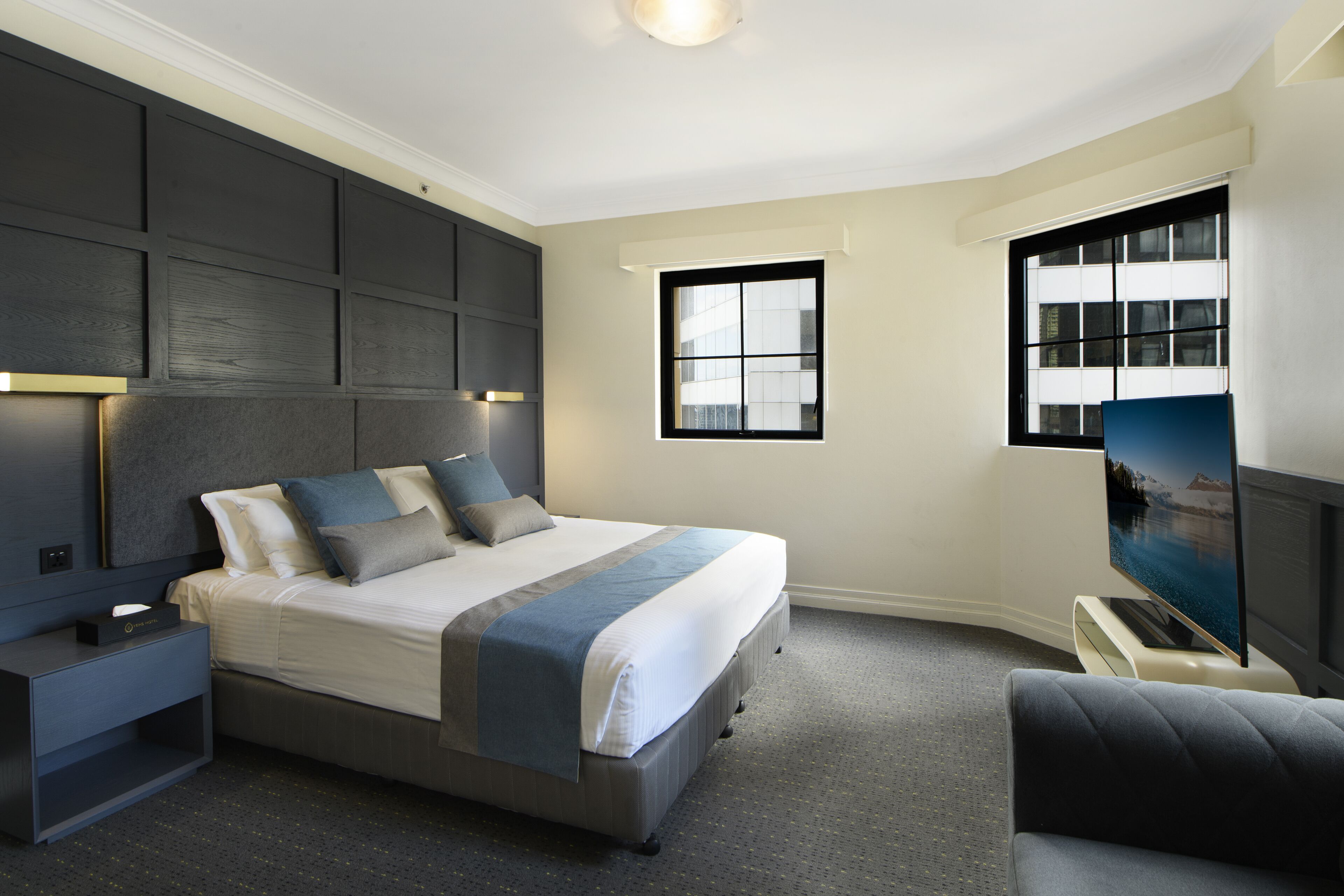 A modern bedroom with a large bed, bedside tables, a TV, and a window.