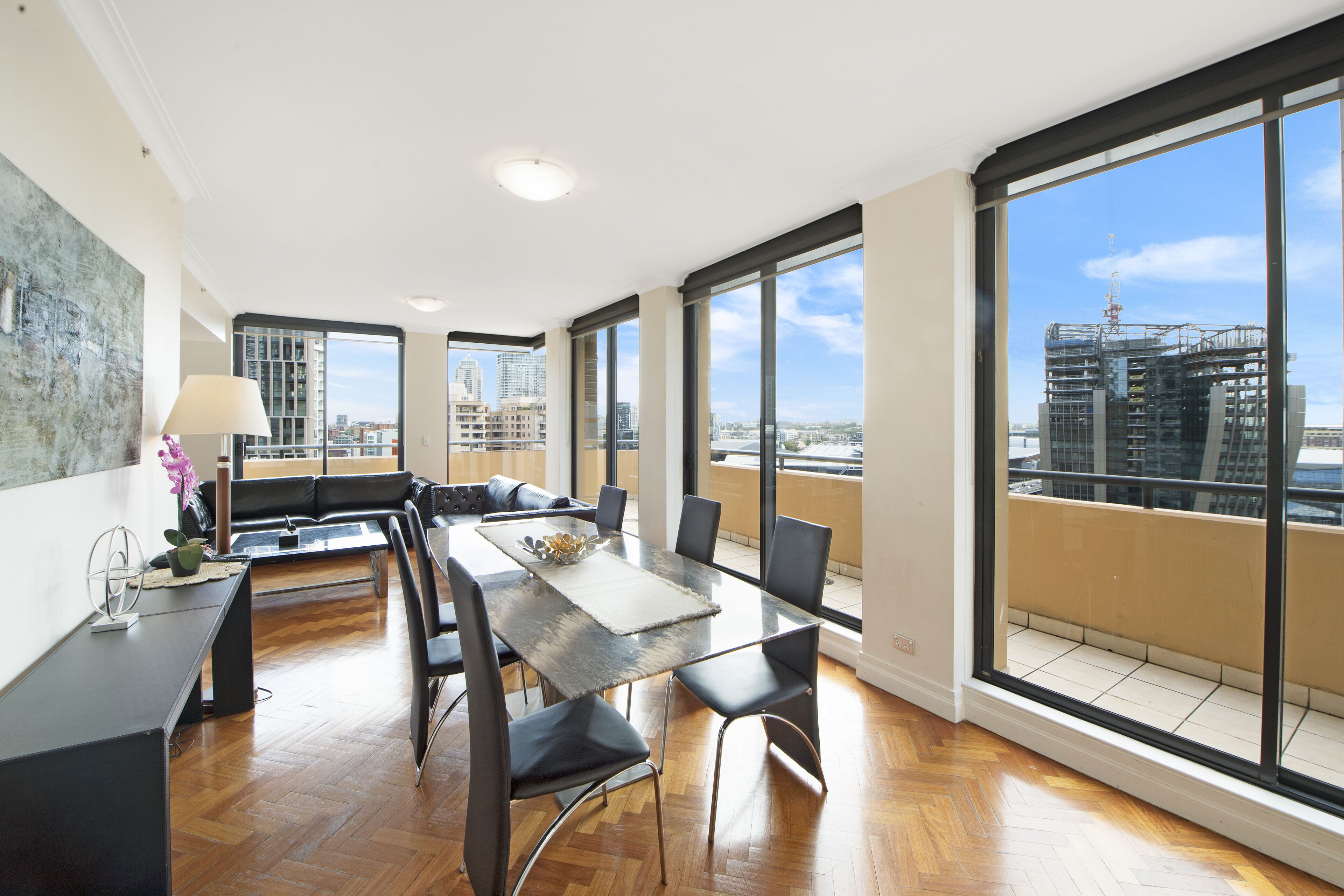 Una habitación amplia con una gran mesa de comedor, sillas y vistas de la ciudad a través de amplios ventanales.