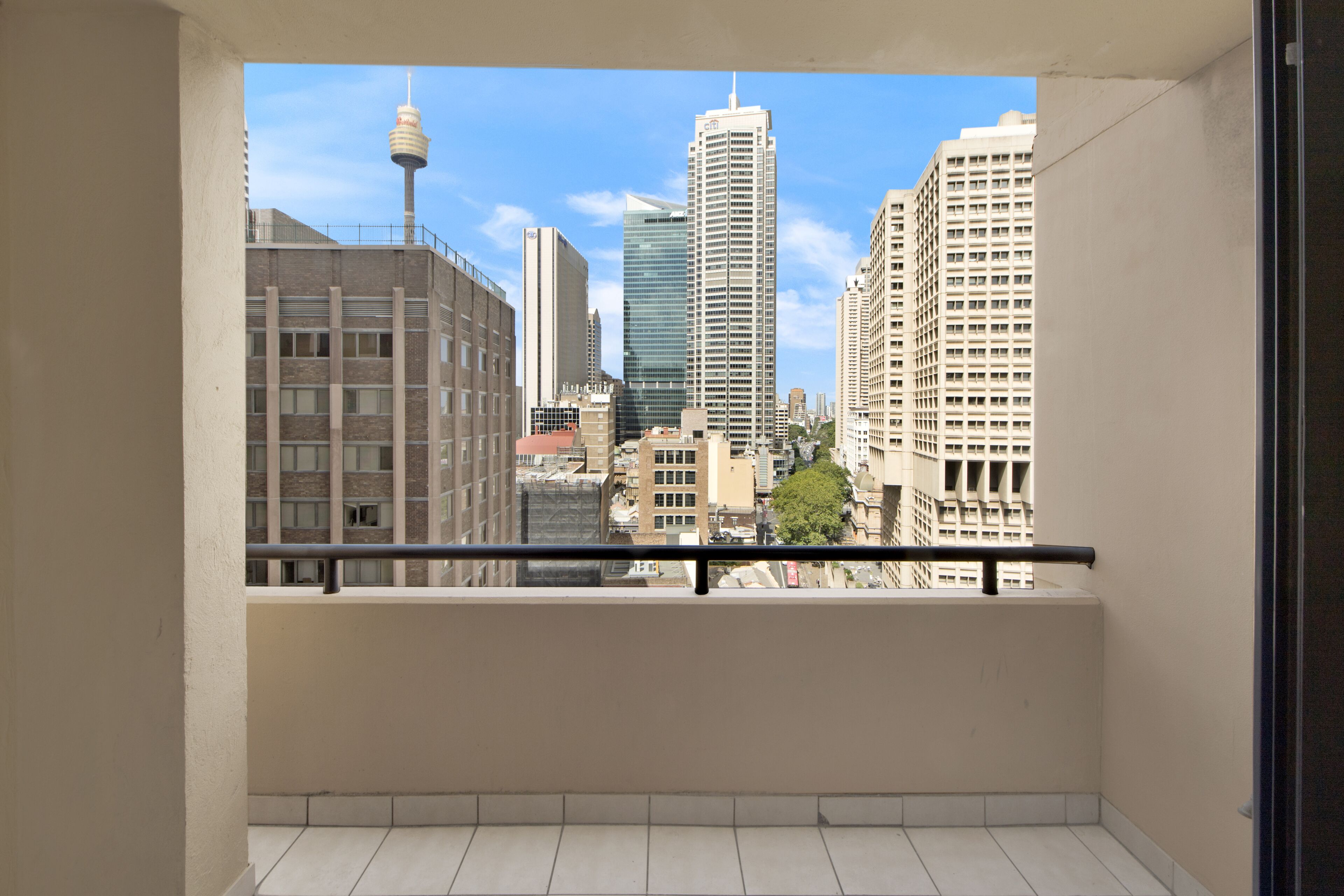 A balcony with a cityscape view, including a tower and modern buildings.