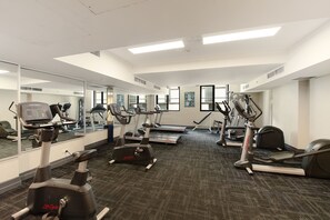 Un gimnasio con máquinas de cardio, espejos y suelo alfombrado.