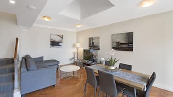 Una sala de estar moderna con un sofá gris, una mesa de comedor con sillas y obras de arte en las paredes.