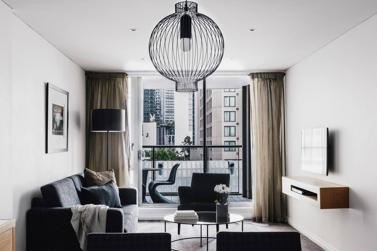 A modern living room with a sofa, coffee table, and a large window with curtains.