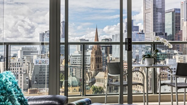 Habitación de hotel moderna con un amplio ventanal que ofrece vistas a la ciudad, incluyendo una catedral destacada y rascacielos.