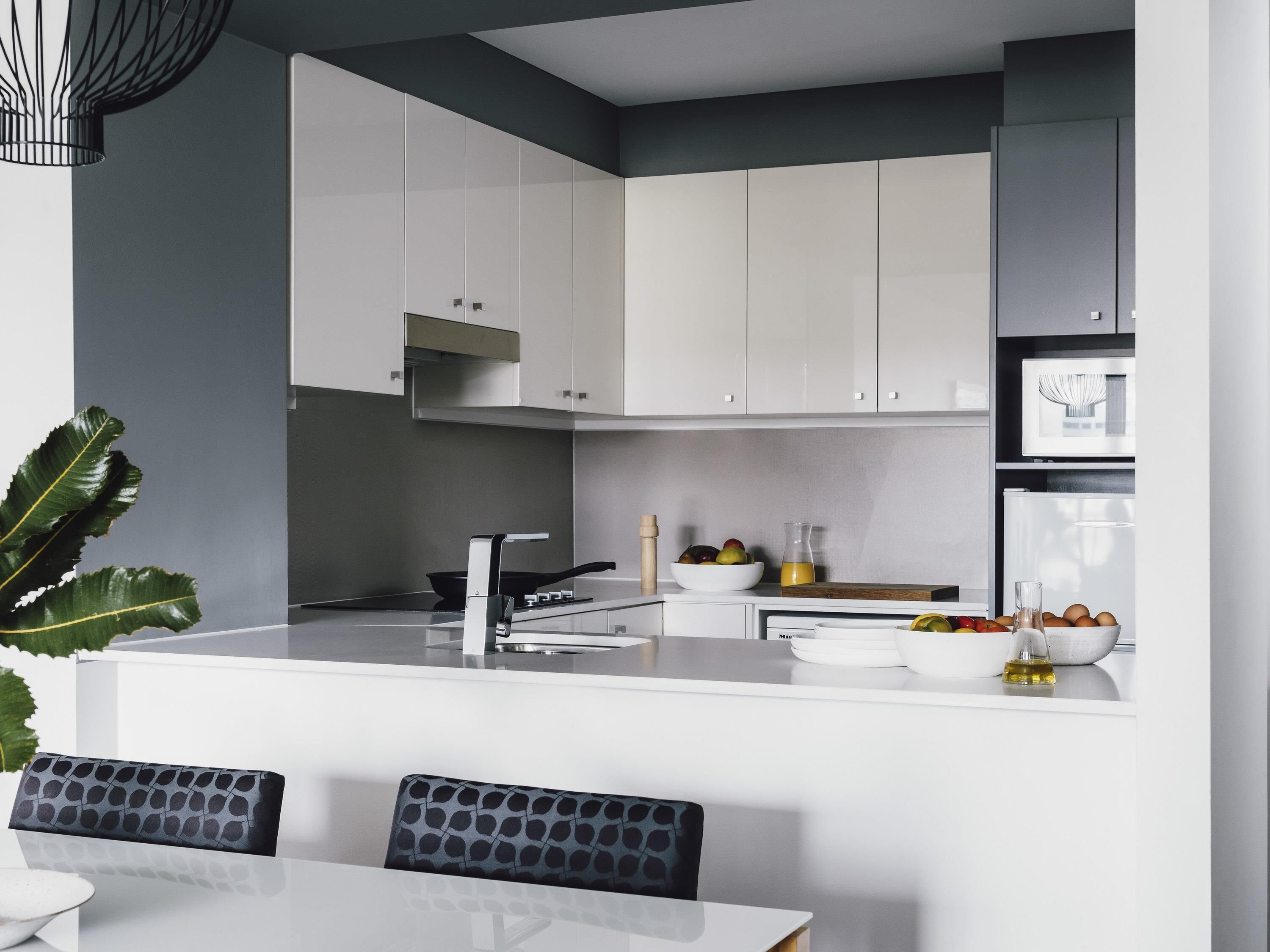 Una cocina moderna con armarios blancos, una estufa negra y un comedor con mesa blanca y sillas negras.