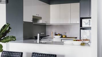 Una cocina moderna con armarios blancos, una estufa negra y un comedor con mesa blanca y sillas negras.