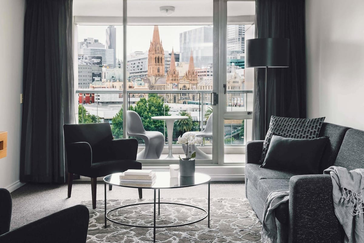 Un salon moderne avec une grande fenêtre, un canapé, une table basse et un fauteuil.