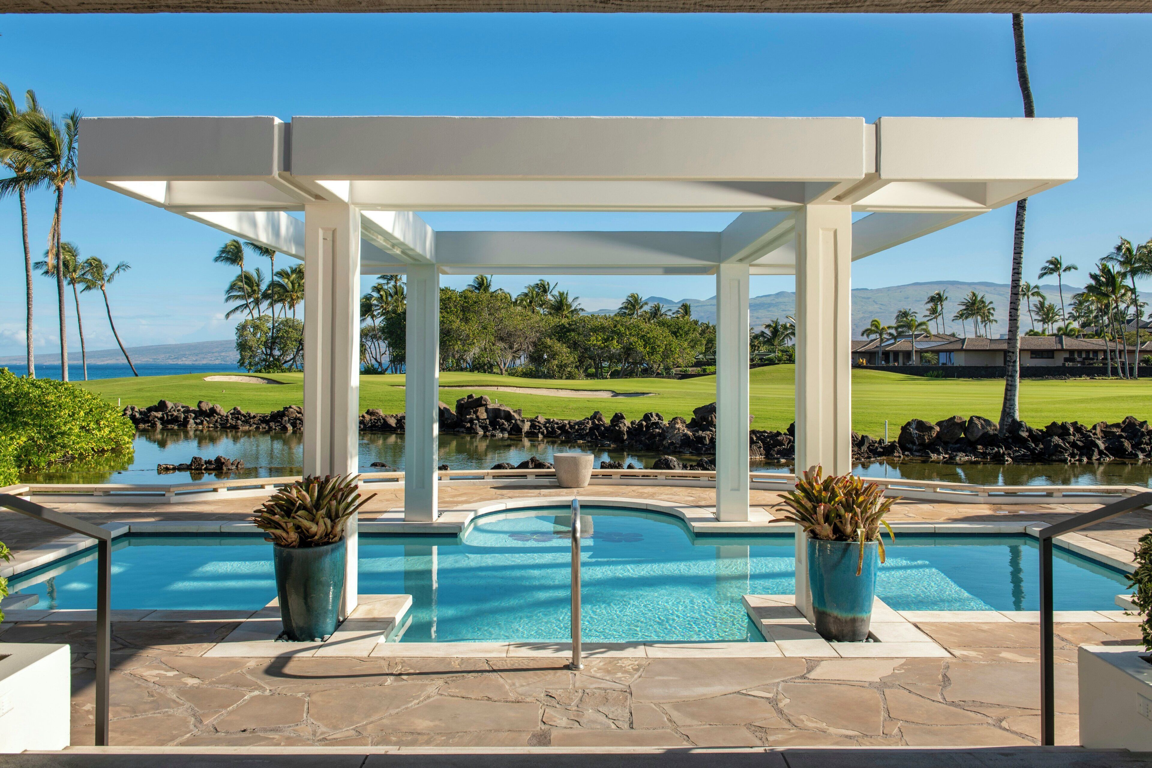 A pool area with a view of a golf course and mountains.
