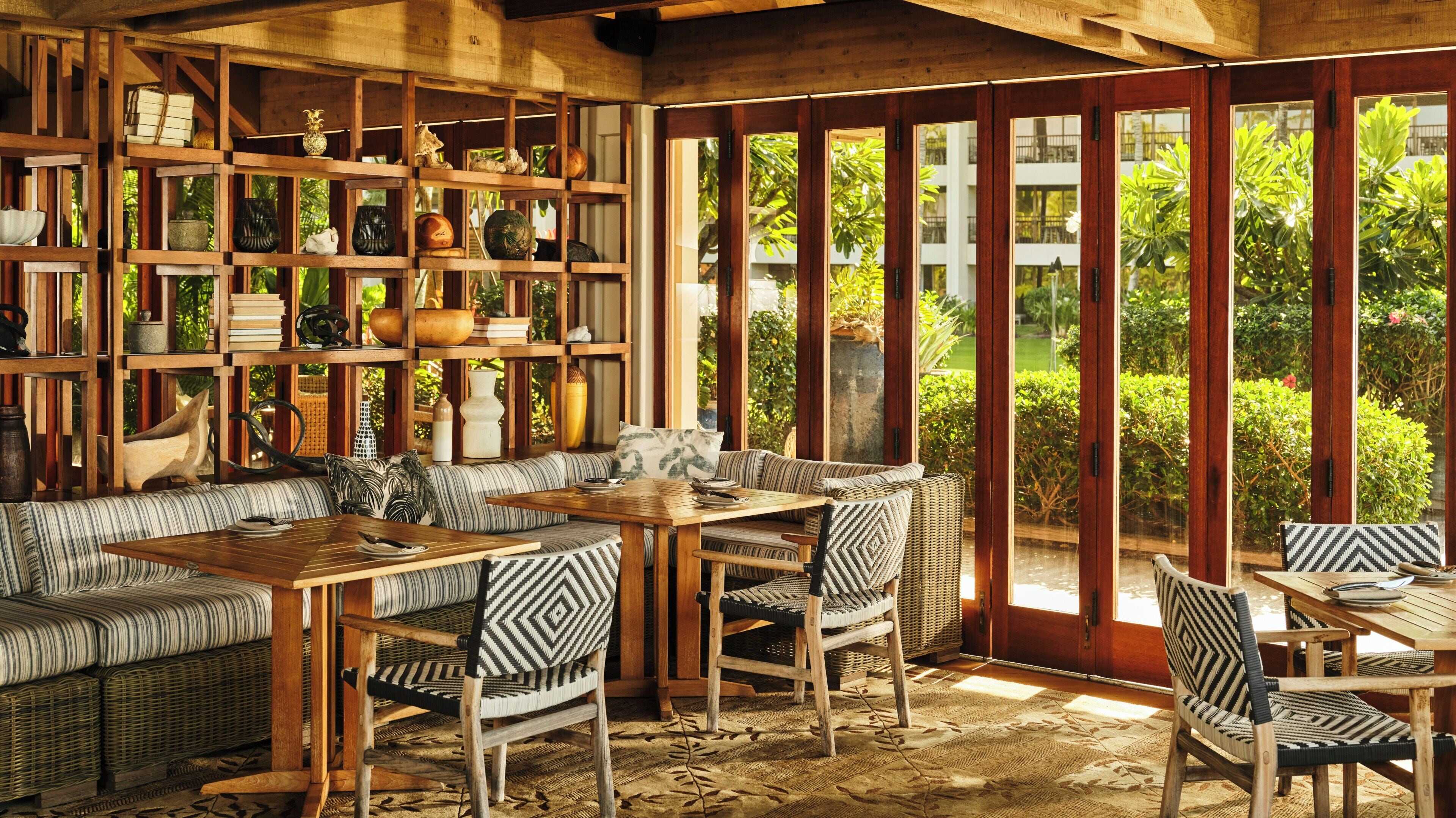 Quarto com teto de madeira, sofá, mesa de jantar, cadeiras e prateleiras com diversos objetos decorativos.