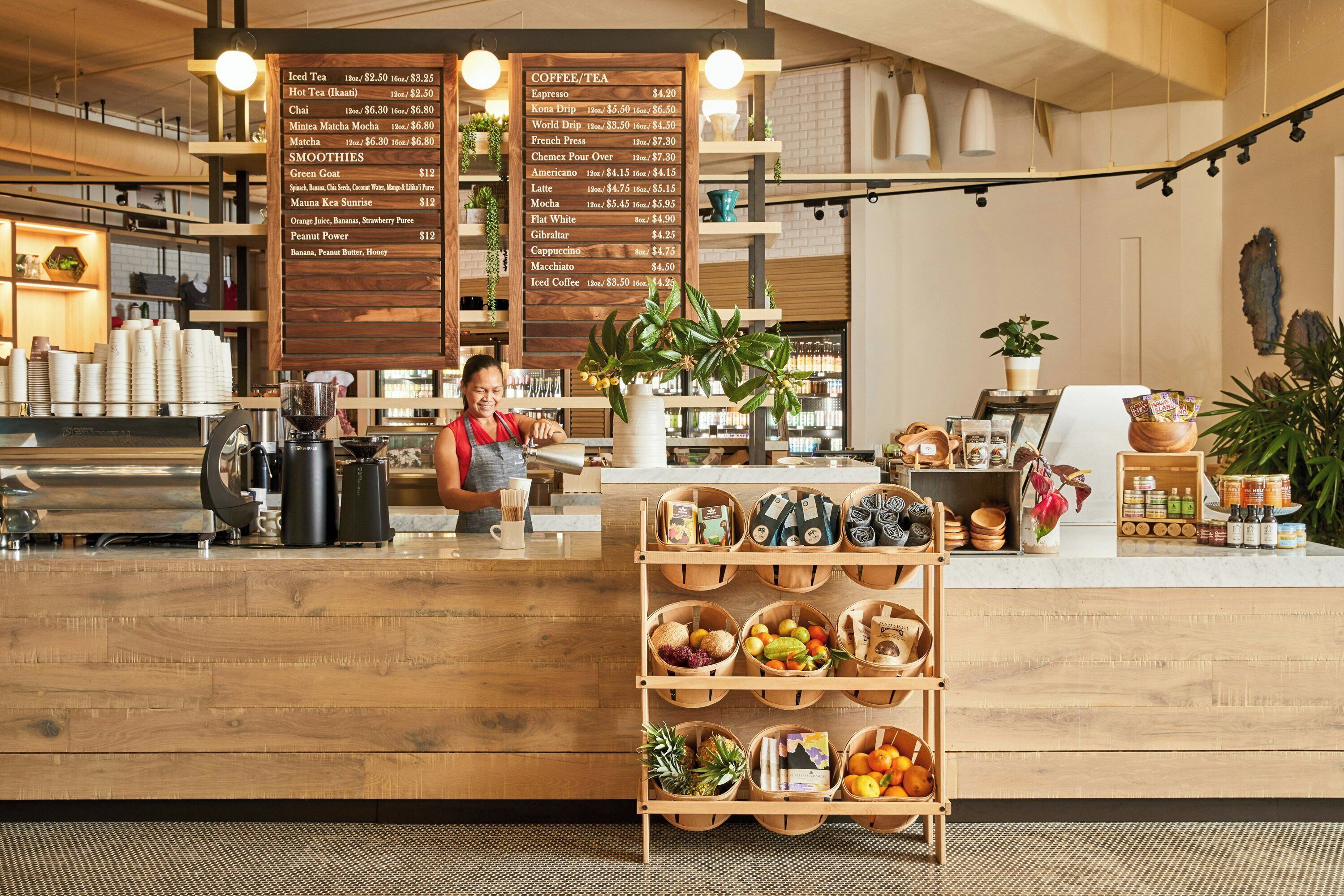 L'intérieur d'un café, avec un comptoir en bois, un tableau affichant le menu et une variété de cafés et de thés proposés.