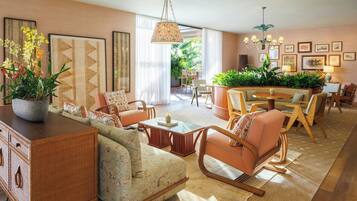 A spacious living room with a sofa, chairs, a dining table, and a large potted plant.
