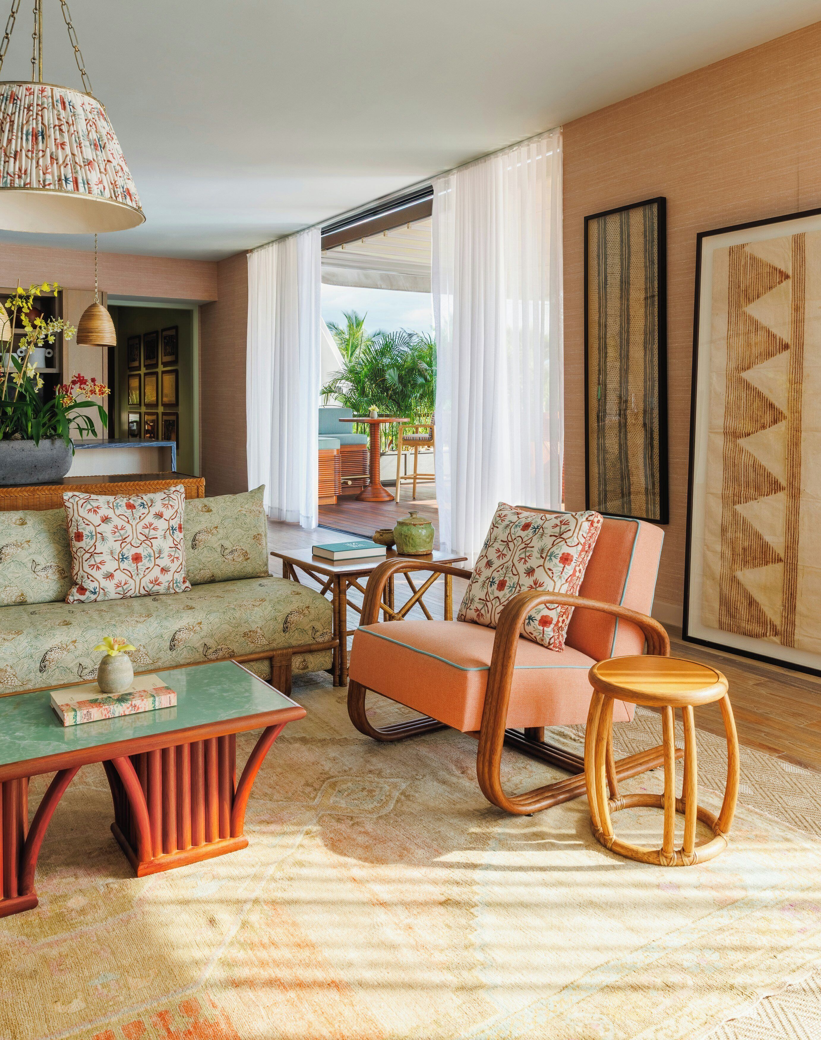A living room with a sofa, armchair, coffee table, and a small stool. There is a window with a view of greenery outside.