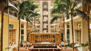 A spacious atrium with a central seating area, multiple floors, and palm trees. - Mauna Lani, Auberge Collection (Kamuela)