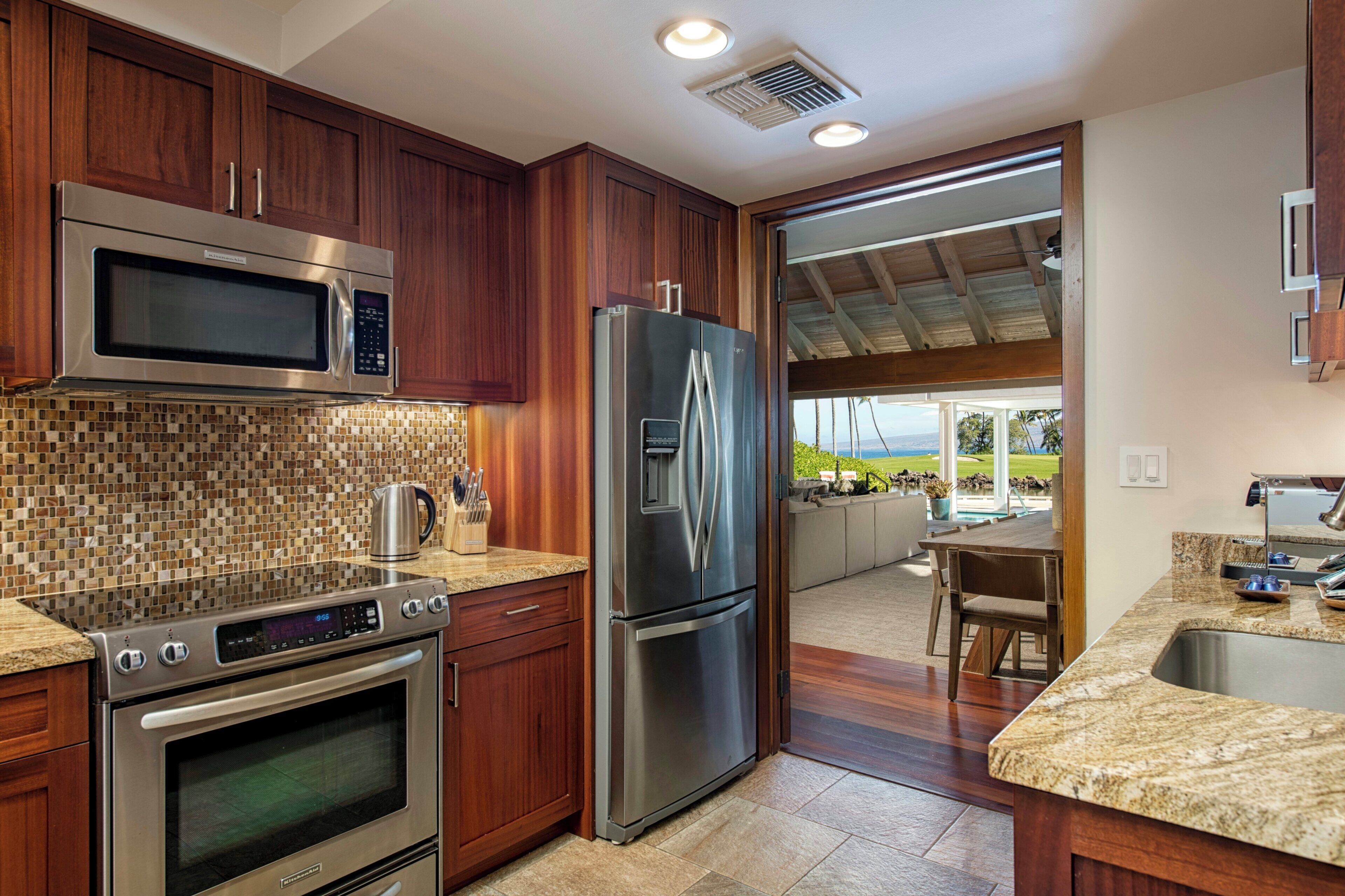 Una cocina moderna con electrodomésticos de acero inoxidable, armarios de madera y vista a un patio exterior.