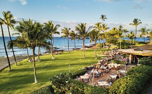 A resort with outdoor dining, palm trees, and a view of the ocean. - Mauna Lani, Auberge Collection (Kamuela)