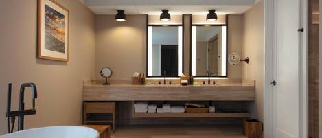 Une salle de bain moderne avec une baignoire, un grand miroir et un meuble-lavabo.