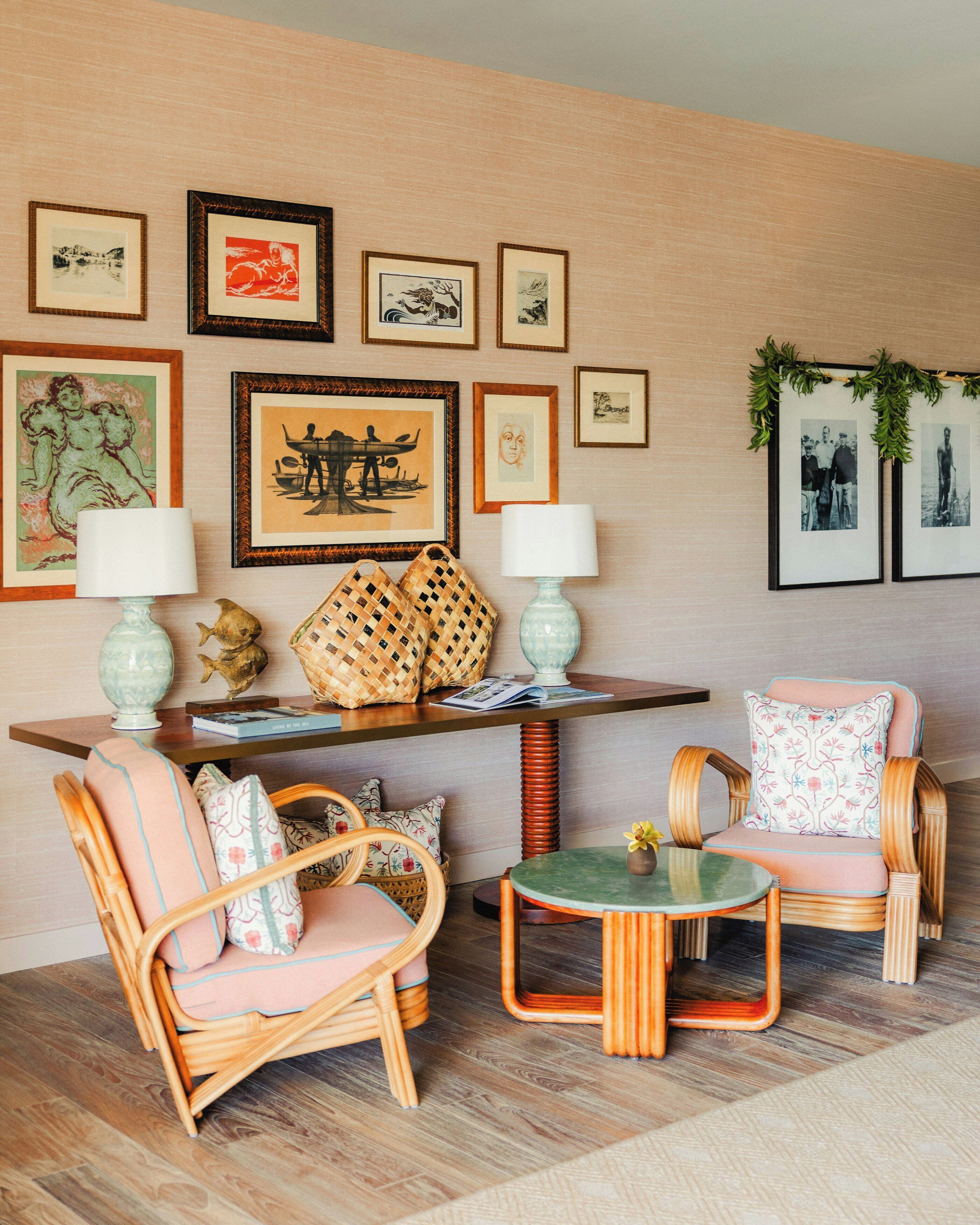 Una habitación con muebles de mimbre, una mesita y cuadros en la pared.