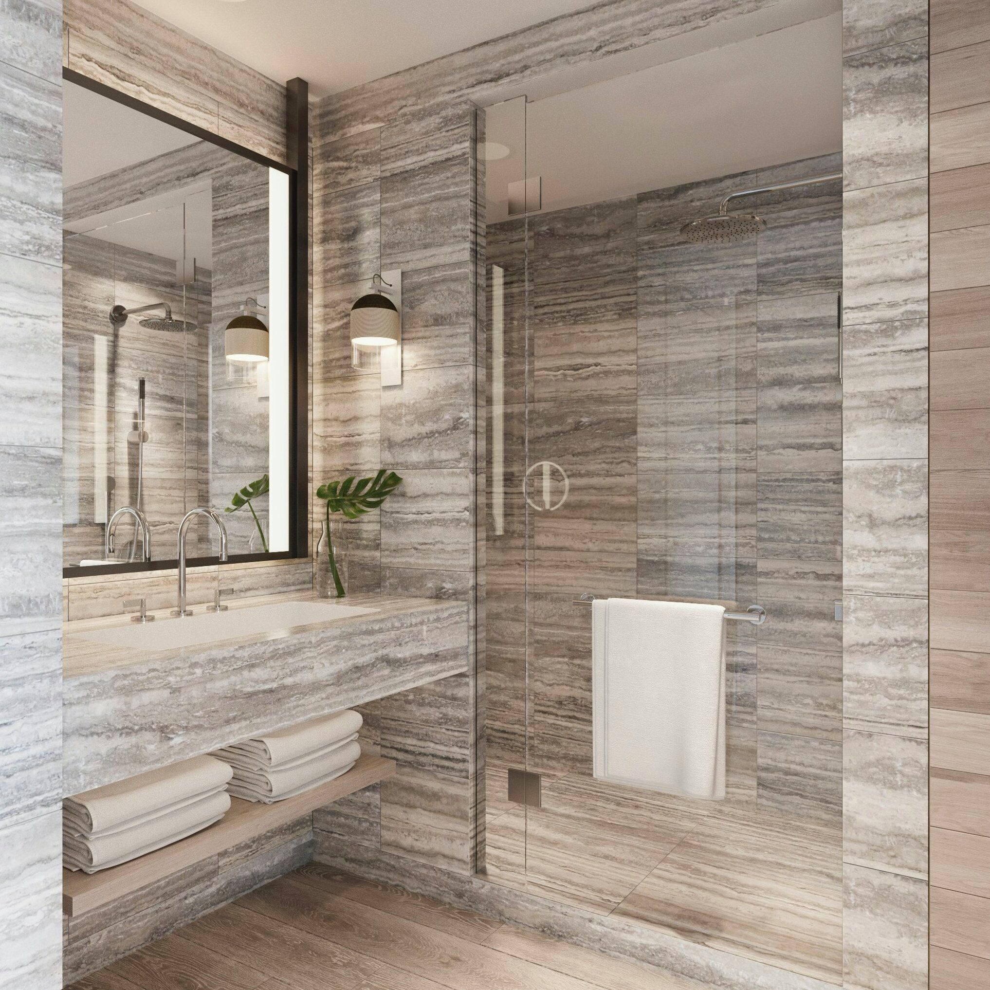 Een moderne badkamer met een marmeren wand, een grote spiegel, een douche en een wastafel met een handdoekhouder.