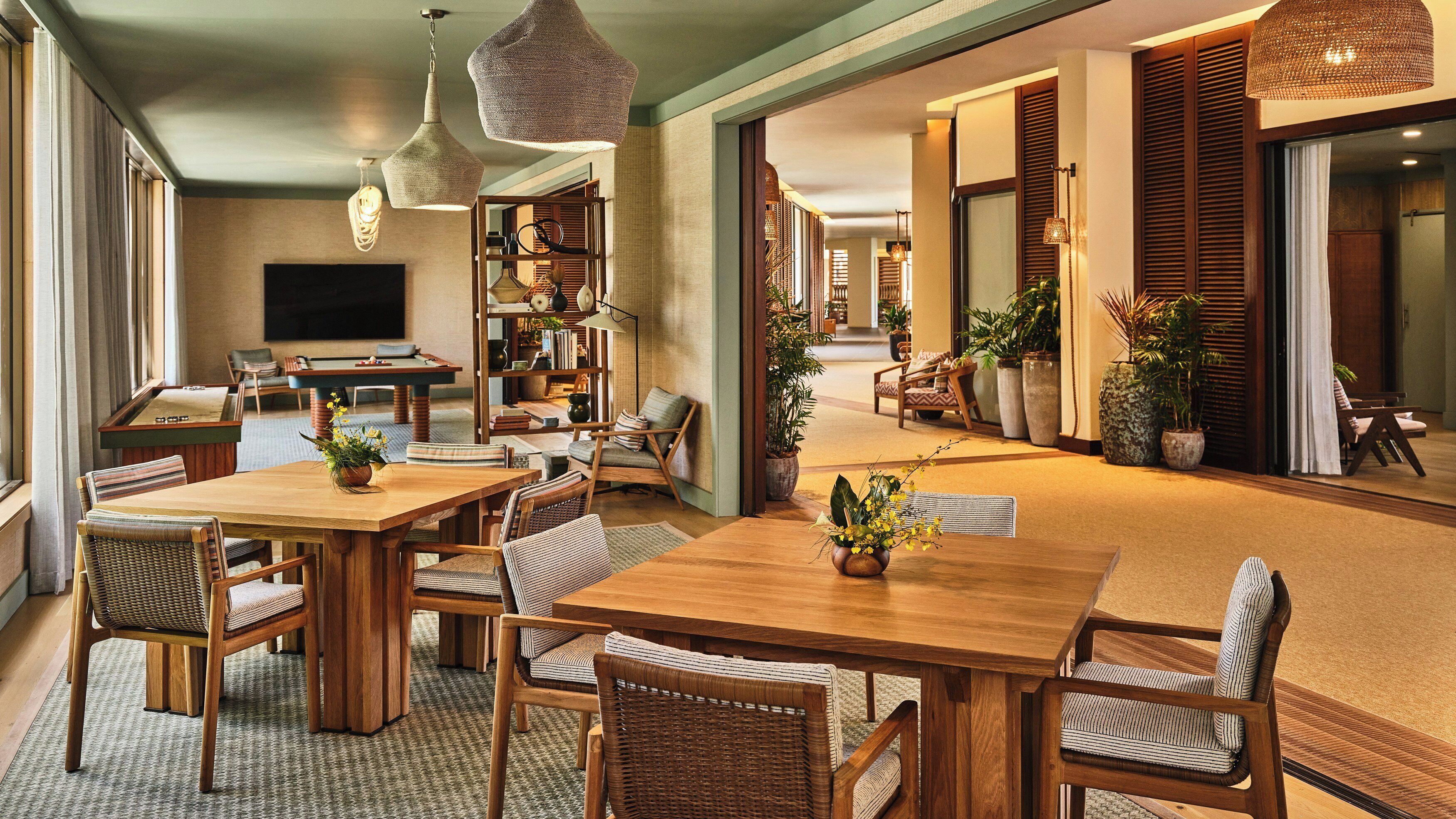 Una habitación amplia con una mesa de comedor de madera, sillas de mimbre, una estantería y un televisor.