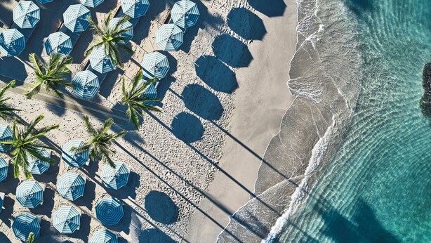An aerial view of a beach with numerous umbrellas and palm trees. - Mauna Lani, Auberge Collection (Kamuela)