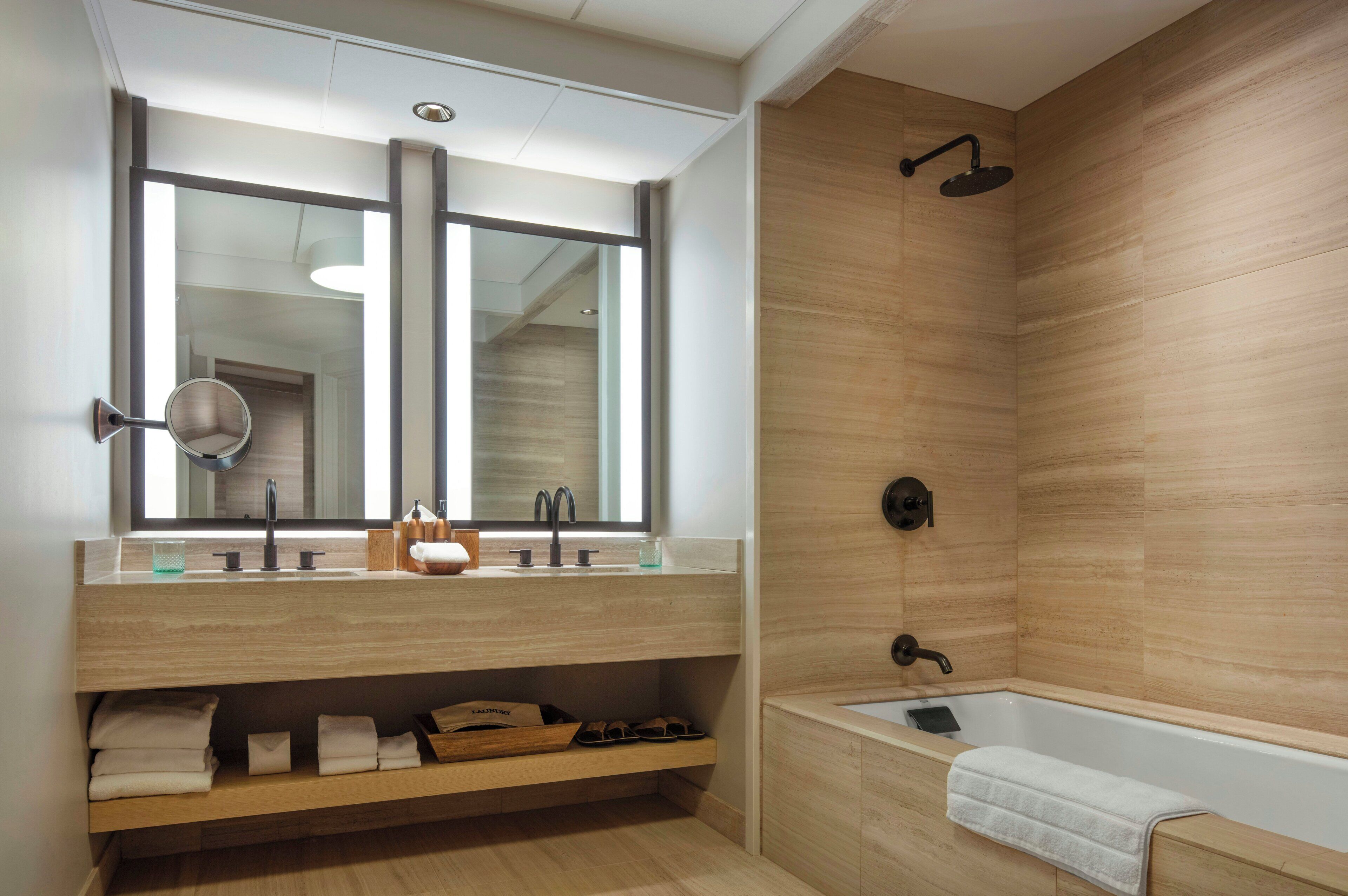 A modern bathroom with a wooden vanity, a large mirror, a bathtub, and a shower.
