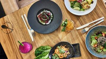 A wooden table with various dishes, cutlery, and a drink.