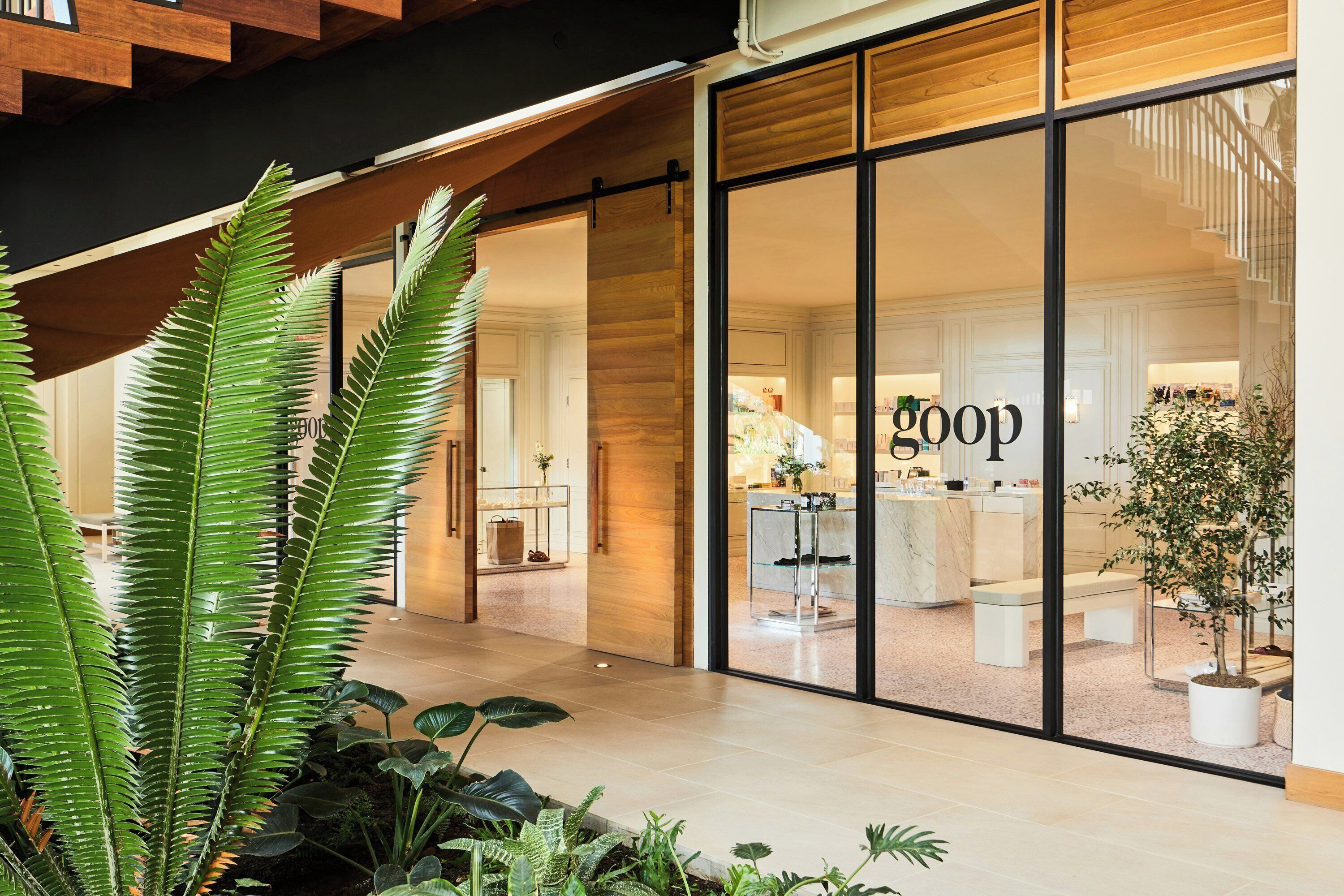 A modern interior with a large glass storefront, wooden beams, and indoor plants.