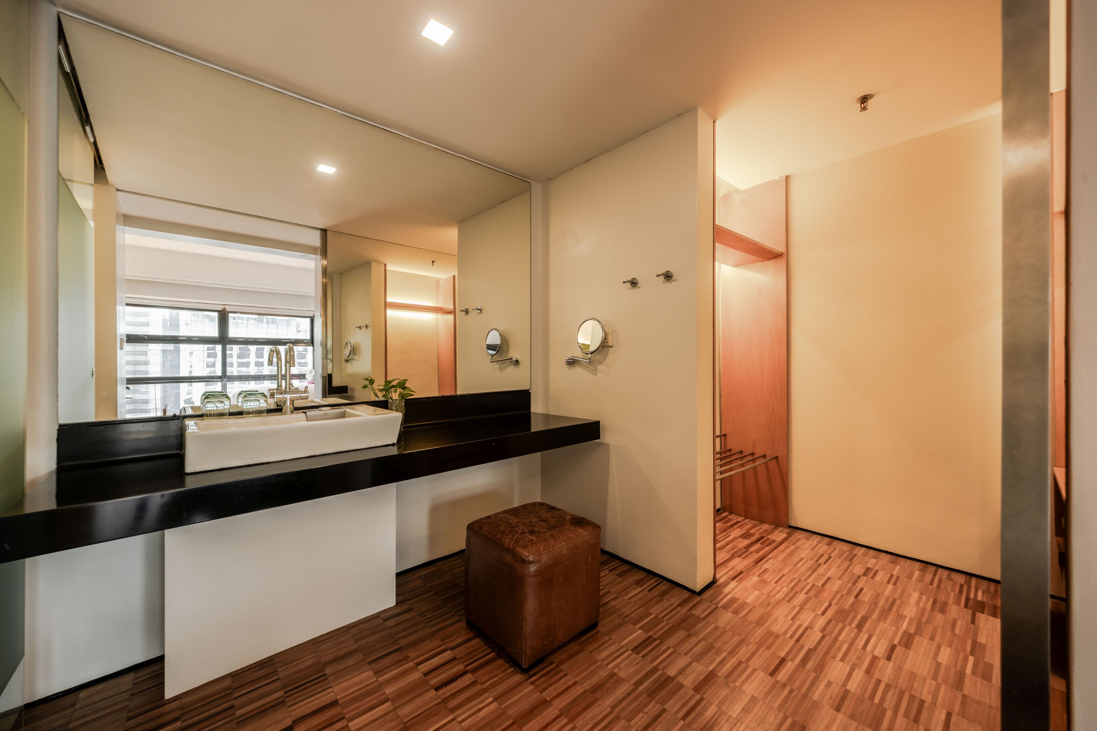 Un baño moderno con un espejo grande, un lavabo y suelo de madera.