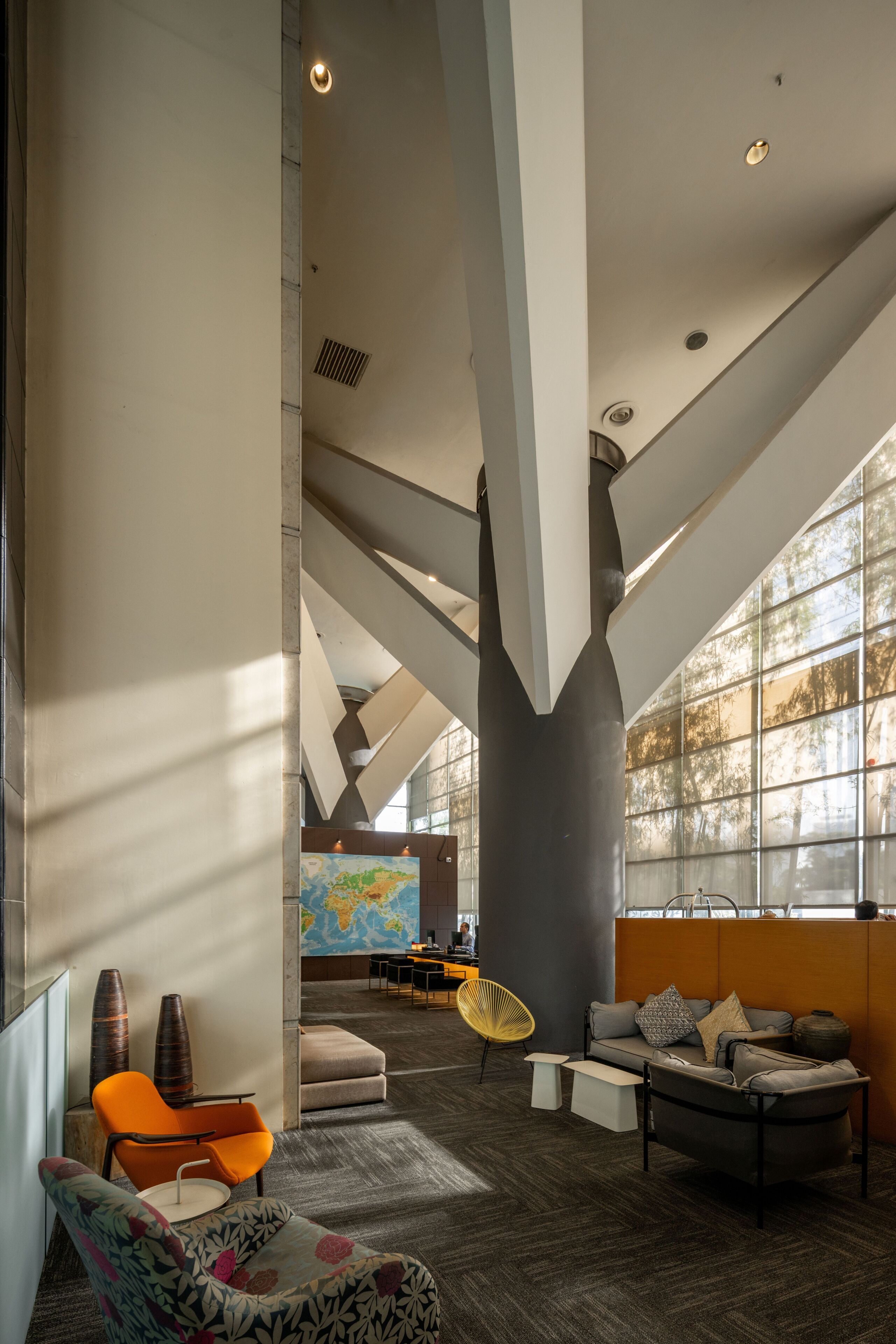 A spacious lobby with high ceilings, a large world map mural, and modern seating arrangements.