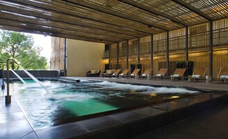 A spa area with a hot tub, lounge chairs, and a bamboo ceiling.